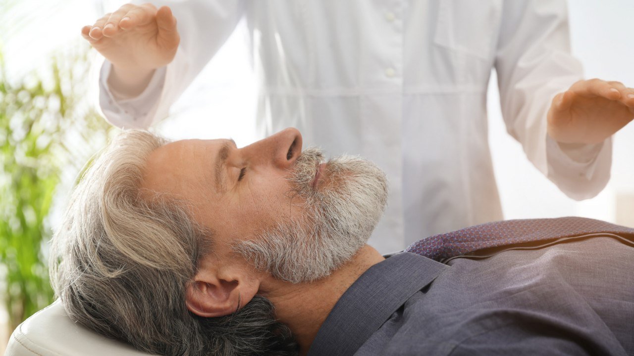 Hombre acostado con imposición de manos - Terapia Energética - Voces Holísticas